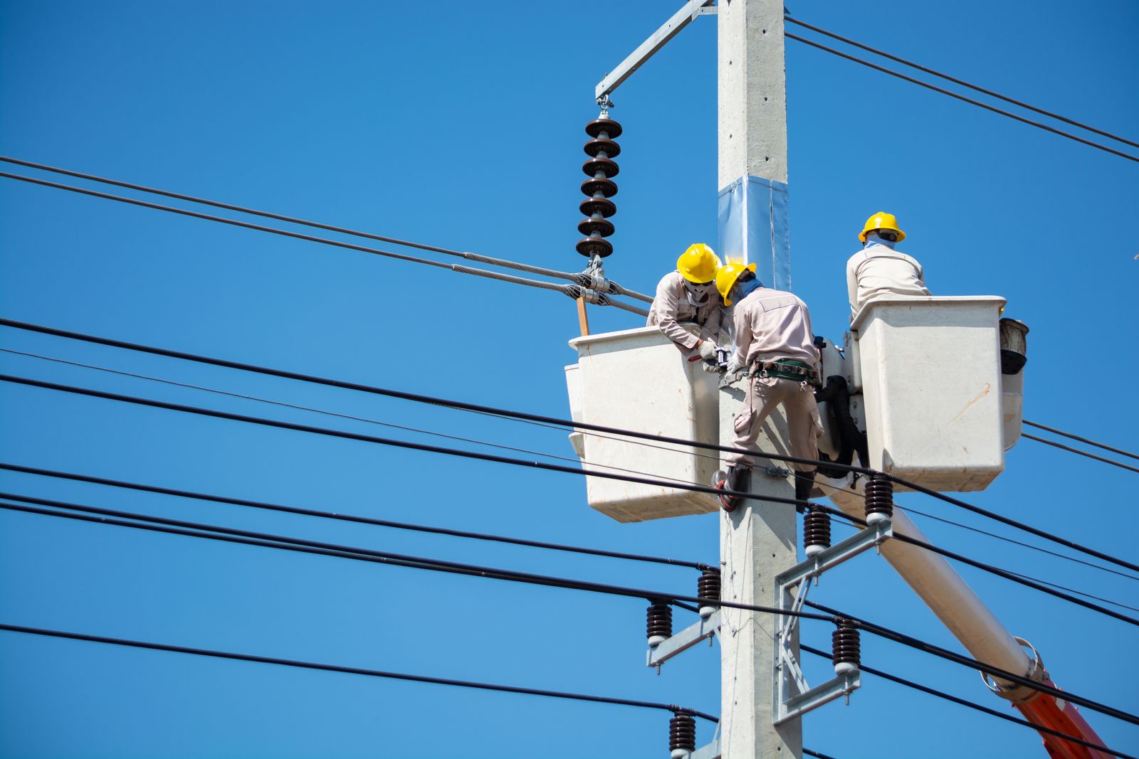 青空の下、電柱で作業を行う晴佑電業の電気工事士
