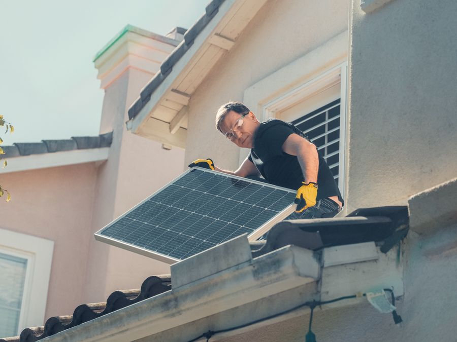住宅の屋根に太陽光パネルを設置する作業員
